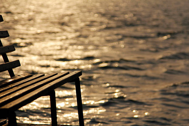 White bench positioned on a wooden pier, overlooking the tranquil sea at sunset, with a stunning, colorful sky illuminating Sopot, Poland