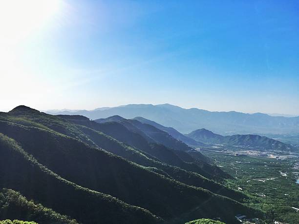A stunning view of a mountain range under a clear blue sky with lush green hills and valleys below.