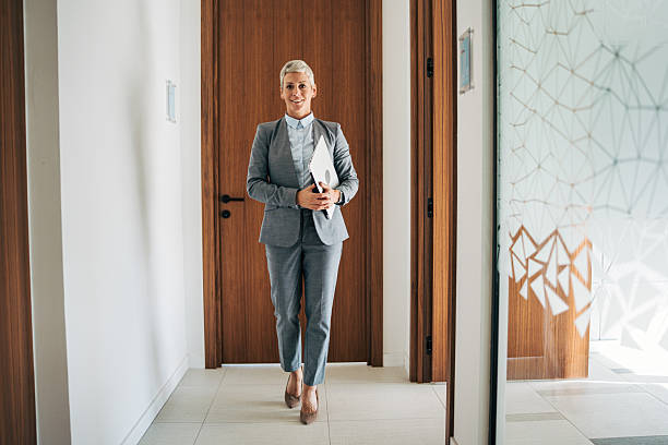 istock Businesswoman walking confidentially through modern office hallway 2243784332