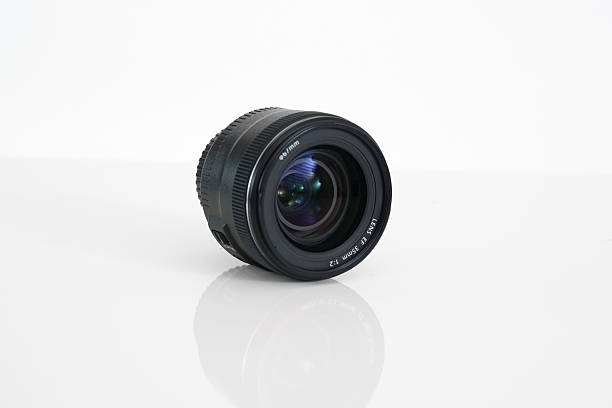istock Rear view of a 35mm camera lens photographed on a white reflective surface. Isolated studio composition. 2243785526