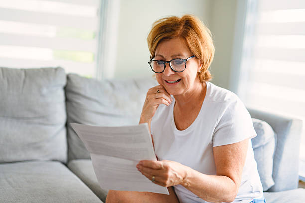 istock mature senior woman check bill on sofa 2243788650