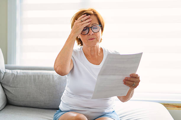 istock mature senior woman check bill on sofa 2243788651