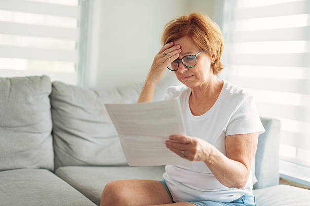 istock mature senior woman check bill on sofa 2243788654