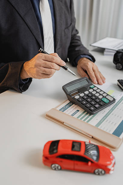 istock A businessman in a suit is calculating car loan options using a calculator and comparison chart, with model cars and car keys on the desk, symbolizing finance, leasing, and investment planning. 2243790989