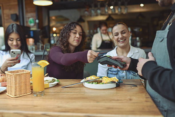 istock Friends At A Modern Lounge Bar Share Breakfast And Pay With Card 2243791210
