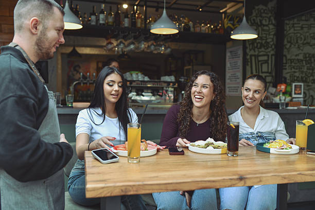 istock Friends At A Modern Lounge Bar Enjoying Breakfast, Drinks, And Laughter Together 2243791444