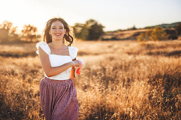 istock Young Woman Running In The Field At Sunset While Holding A Hat 2243793421