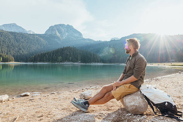 istock Man Relaxing by Mountain Lake at Sunrise 2243794224