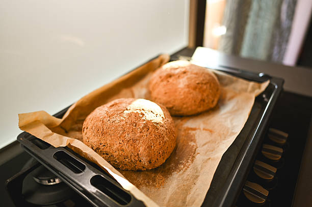 Two fresh baked round loaves of bread on parchment paper