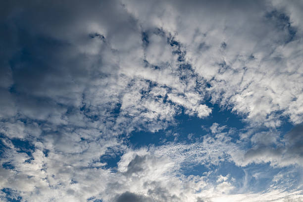 Patches of blue sky with dramatic, dark clouds in various textures. Ideal for weather, atmosphere, and abstract sky themes.