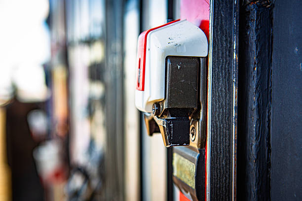 A close-up of a vintage downhill ski binding, painted red, white, and black, that’s been screwed to the weathered exterior of an old ski lodge. The metal hardware shows patina, scuffs, and chipped paint. The shallow depth of field throws the background into creamy bokeh, emphasizing the binding as nostalgic alpine décor. Daytime, dry conditions. Static shot.