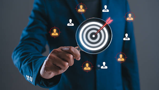 istock A person in a suit holds a magnifying glass over a target, symbolizing focus on identifying key individuals in a professional context. 2243802553