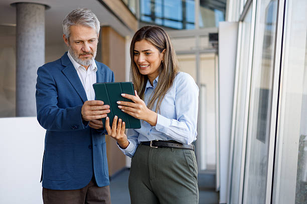 istock Diverse business partners collaborating, discussing project on digital tablet in modern office hallway 2243804743