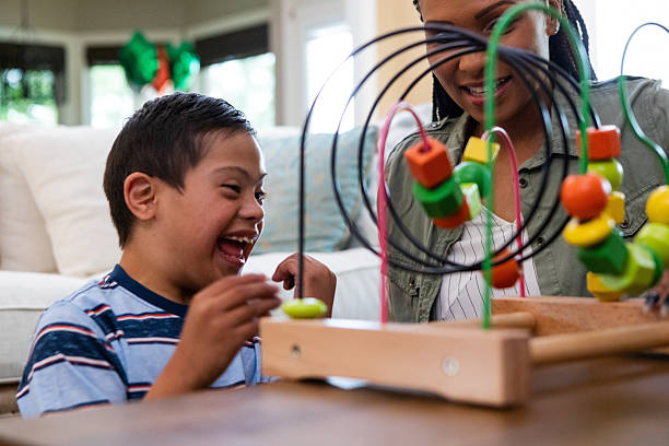 istock Joyful child with Down syndrome interacts with bead toy alongside woman. 2243809312
