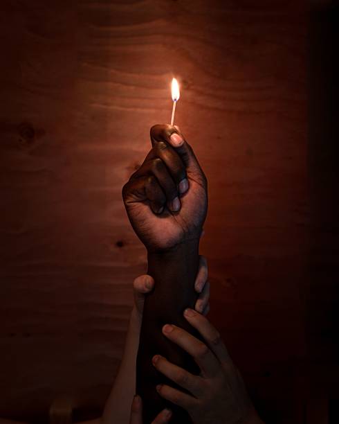 istock Hand holding lit matchstick symbolizing hope and unity. 2243810379