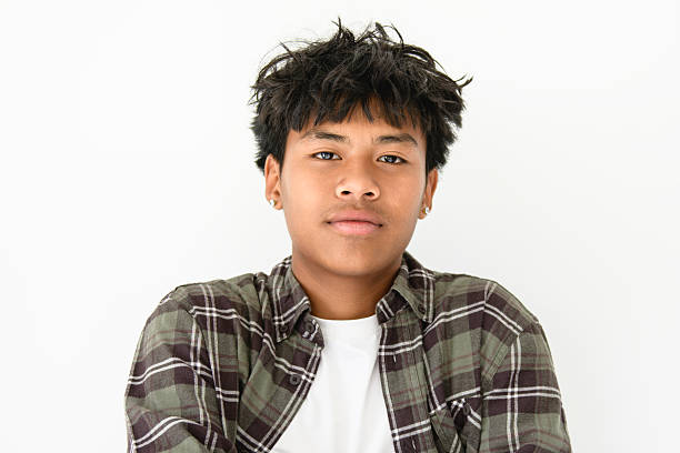Teenaged boy wears rainbow wristband and holding rainbow flags, lgbtqai symbol, in front of wall, concept for calling out all people to respect human rights of lgbtqai people around the world.