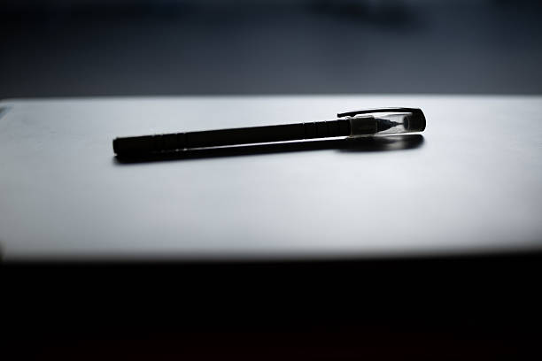 A sleek pen with transparent cap on reflective black and grey surface