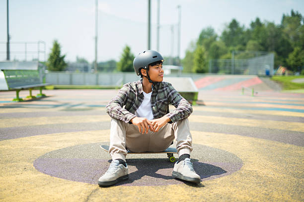 A young African-American boy wearing a backpack and holding a skateboard