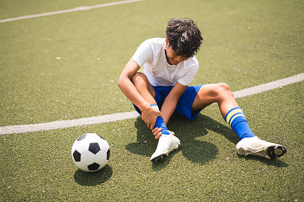 istock nice Boy with soccer ball outside on field having injury 2243814097