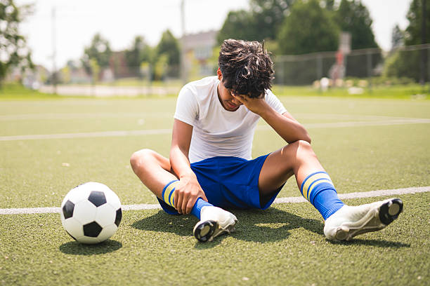 istock nice Boy with soccer ball outside on field having injury 2243814100