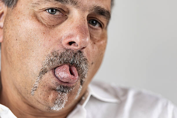 Mature male with facial hair curling his tongue