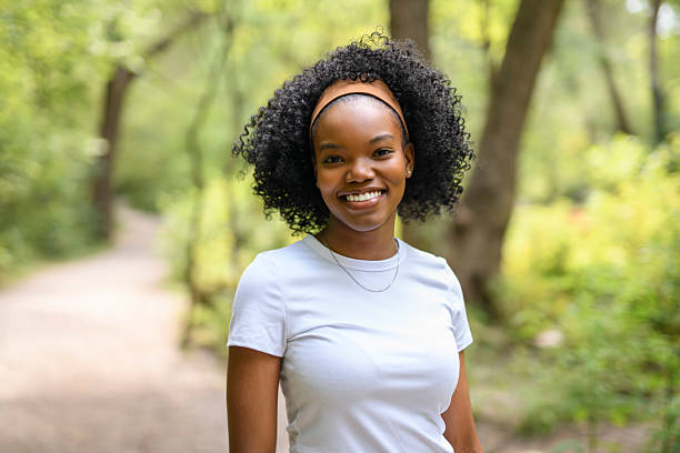 A Young black woman standing infront of a forest