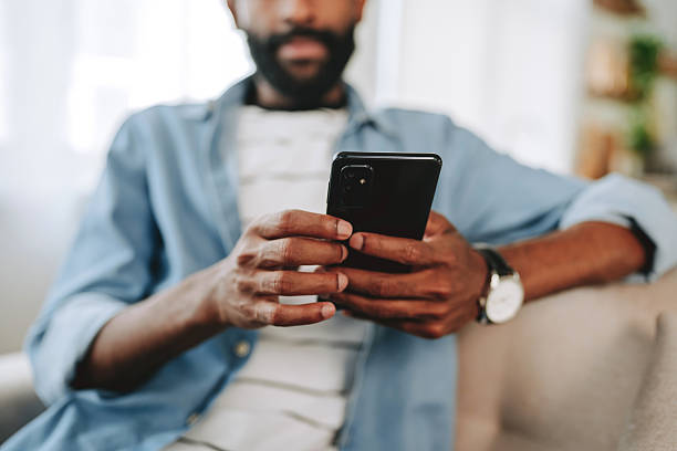 istock Close-up of man using smartphone while sitting on sofa at home 2243821172