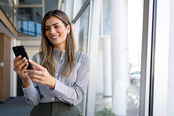 istock Professional woman smiling, communicating on mobile phone inside modern office building, enjoying successful career 2243823371