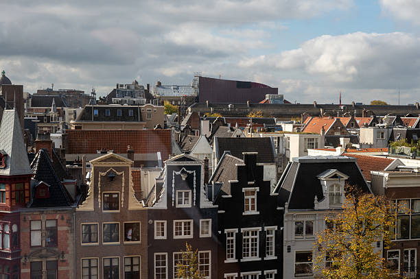 amsterdam, netherlands - January 15 2025: People stroll along a street with a mix of traditional and contemporary architecture while bicycles and the anne frank house museum