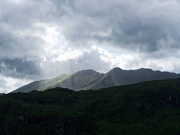 istock Cloudy sky over rugged, green mountain terrain. Ideal for travel & nature projects. 2243824453