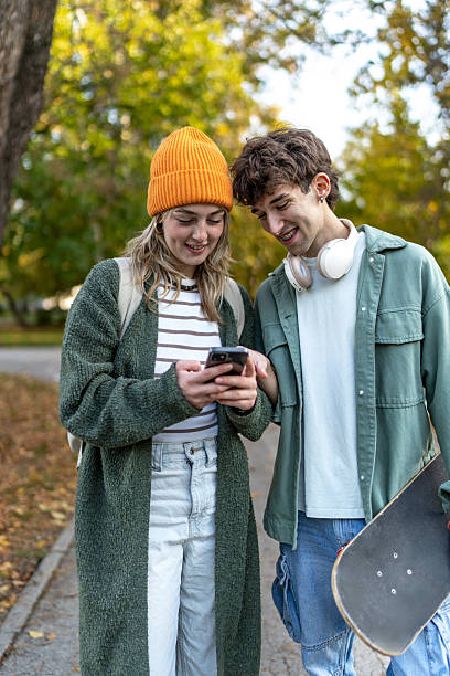 istock Teenagers sharing smartphone screen in autumn park 2243825018