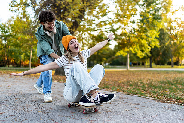 istock Young couple playing with skateboard in autumn park 2243826582