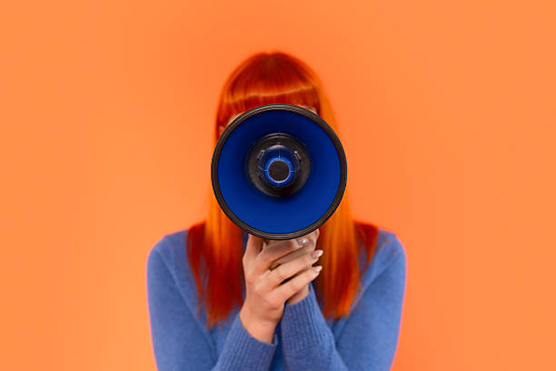 istock Brightly colored woman holds megaphone against a vibrant orange backdrop while engaging in advocacy or communication 2243828122