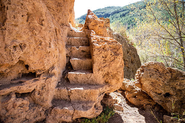 istock Visitors navigate path lined with ancient stone steps, leading through unique rocky terrain in scenic area. Sunlight filters through trees as nature surrounds them 2243828222