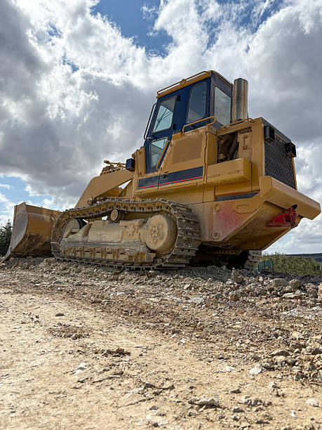 Bulldozer at a construction site. Construction machinery bulldozer, dozer. A rear view bulldozer digging up the earth with sunny cloudy sky background