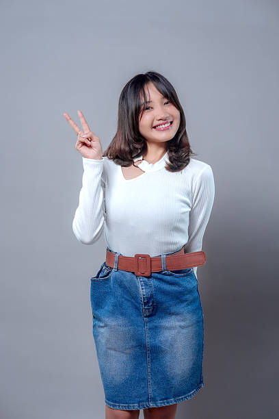 istock Smiling Asian Woman Making Peace Sign Gesture 2243838130