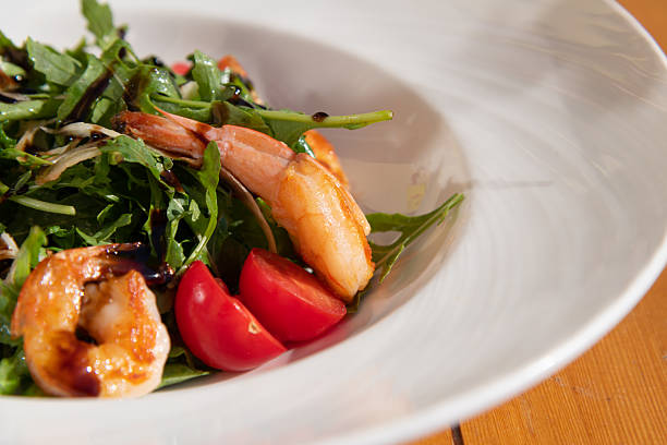 Succulent grilled shrimp on top of fish fillet, accompanied by fresh greens and lemon