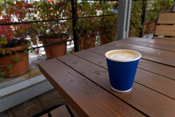 Cozy coffee cup on a wooden table at an outdoor cafe with plants