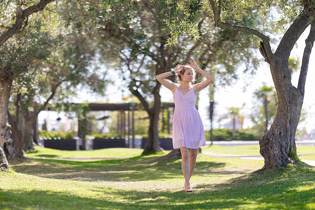 Young woman gracefully moving on green grass, expressing freedom and nature in a park