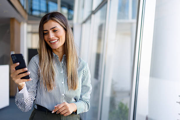 istock Young businesswoman smiling, using mobile phone for business communication and networking in modern office 2243841565