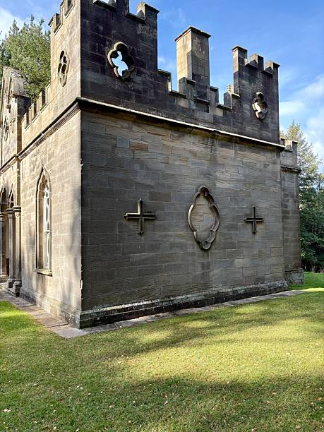 istock A charming stone building with gothic windows and battlements stands amid lush greenery. Pointed arches and ornate details give it a castle-like elegance, blending history with serene natural beauty. 2243841686