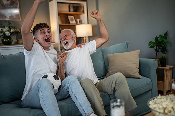 istock Father and son watching soccer game cheering at home 2243844515