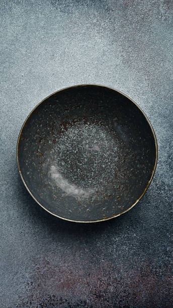 istock Ceramic dark round textured plate. Close up on gray concrete background. Free space for text. 2243846042