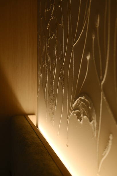 Textured wall shows pale plant art, lit from below.