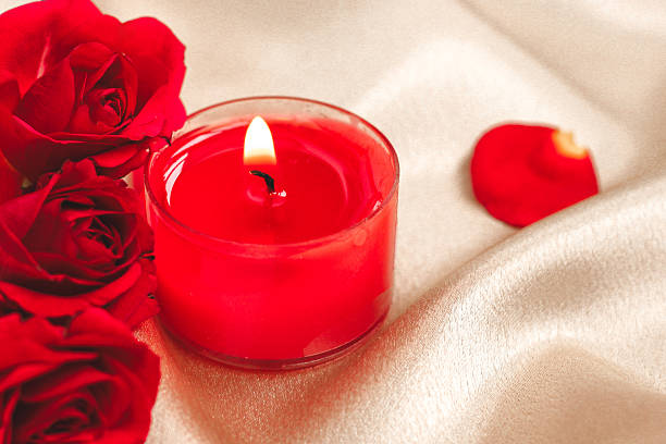 istock Soft candlelight illuminates red roses and petals on elegant satin fabric for romantic setting 2243848075