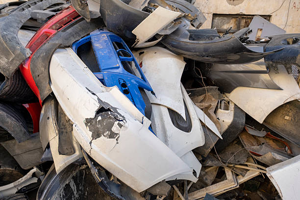 A burnt car sits on a hydraulic lift amidst the complete wreckage of an auto repair shop destroyed by fire. The ruins are covered in snow and ice on a sunny winter day, showing the total loss of the small business property.