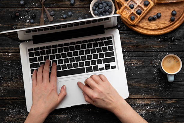 istock Hands typing on laptop with coffee and waffles on rustic desk 2243849441