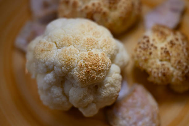 A close-up of delicious, golden-brown roasted cauliflower florets in a warm bowl. A perfect, healthy, and savory homemade meal, ready to be enjoyed.