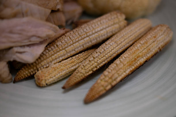 Fresh baby corns arranged on a vibrant yellow background.