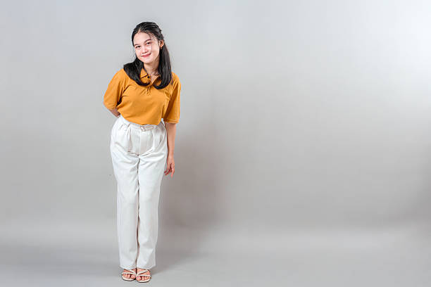 istock Smiling young Asian woman with a sweet and charming expression, slightly tilting her head while leaning forward. Her gentle face and warm smile evoke friendliness and joy. 2243851382